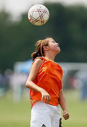 Young girl heading soccer ball